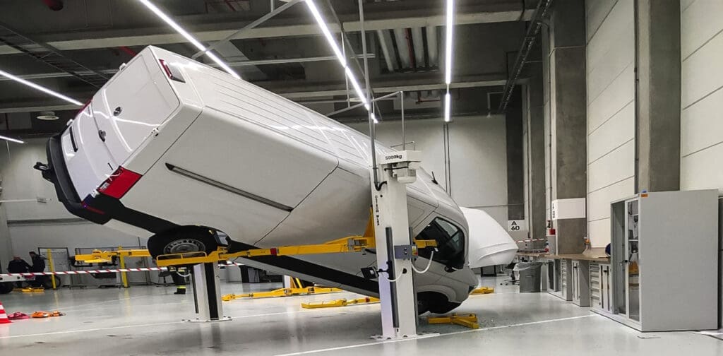 Spadnięcie dużego samochodu z podnośnika dwukolumnowego w warsztacie samochodowym